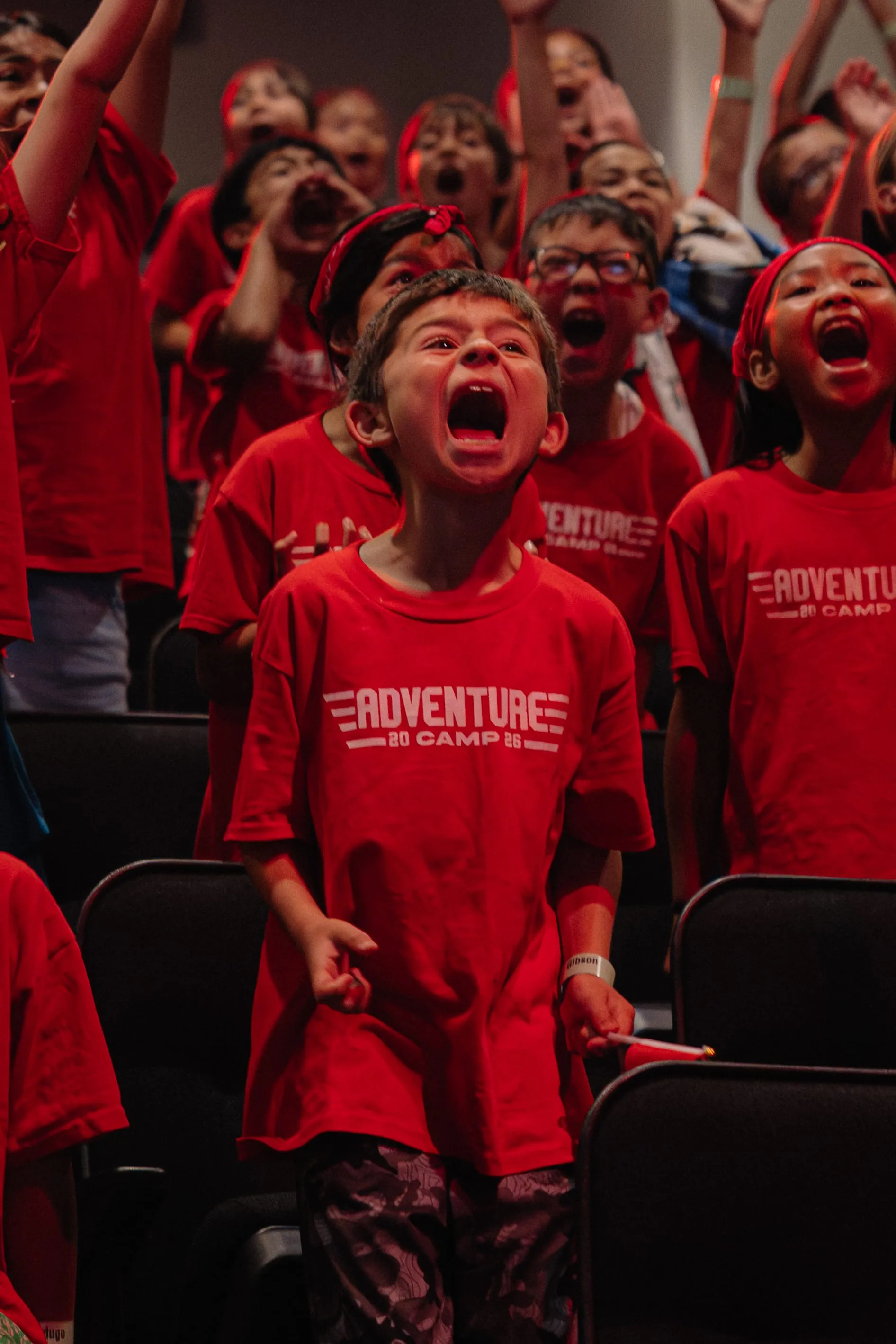 Campers cheer and sing along during an evening rally in the auditorium.