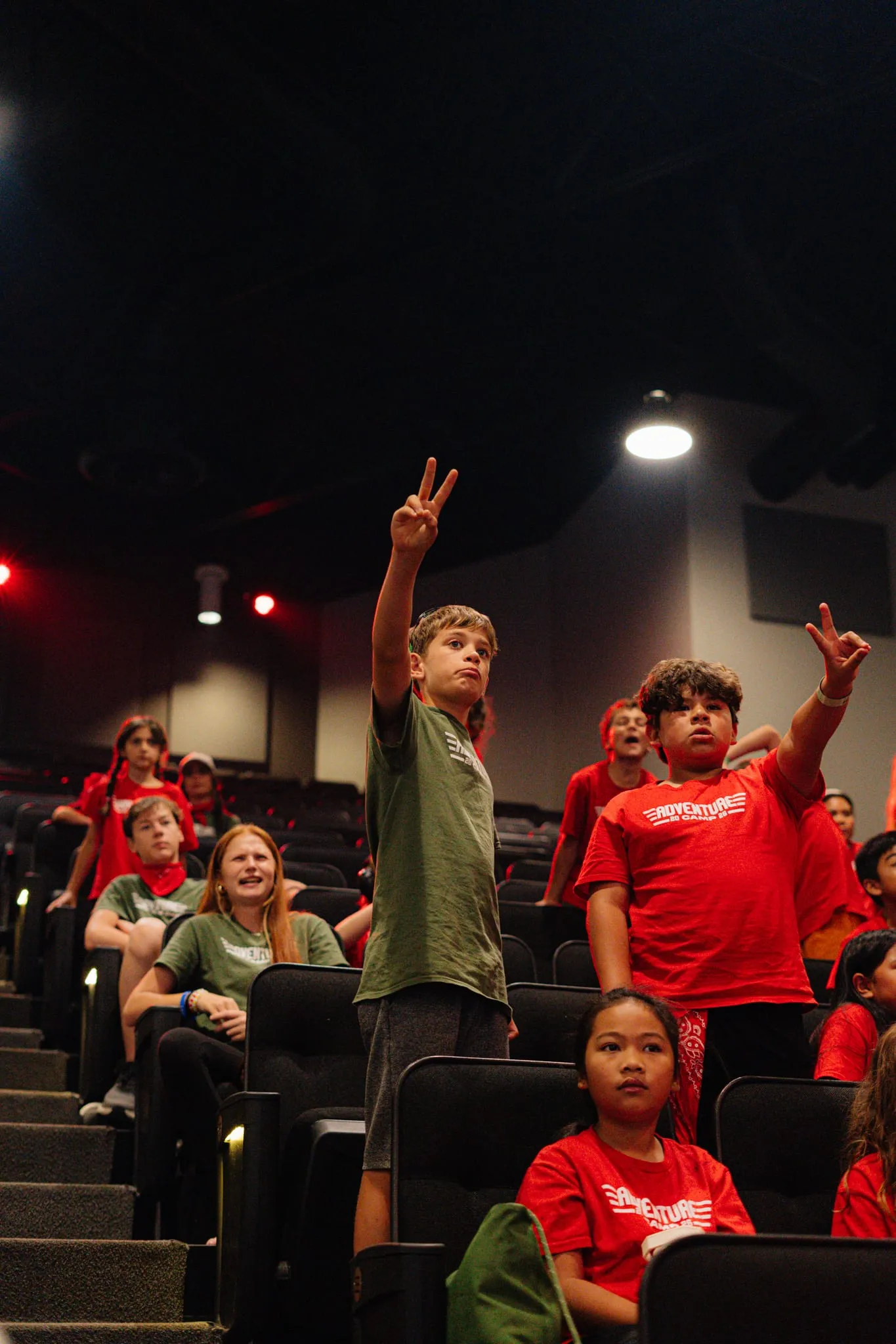 Two campers throw up peace signs from their seats in the theater.