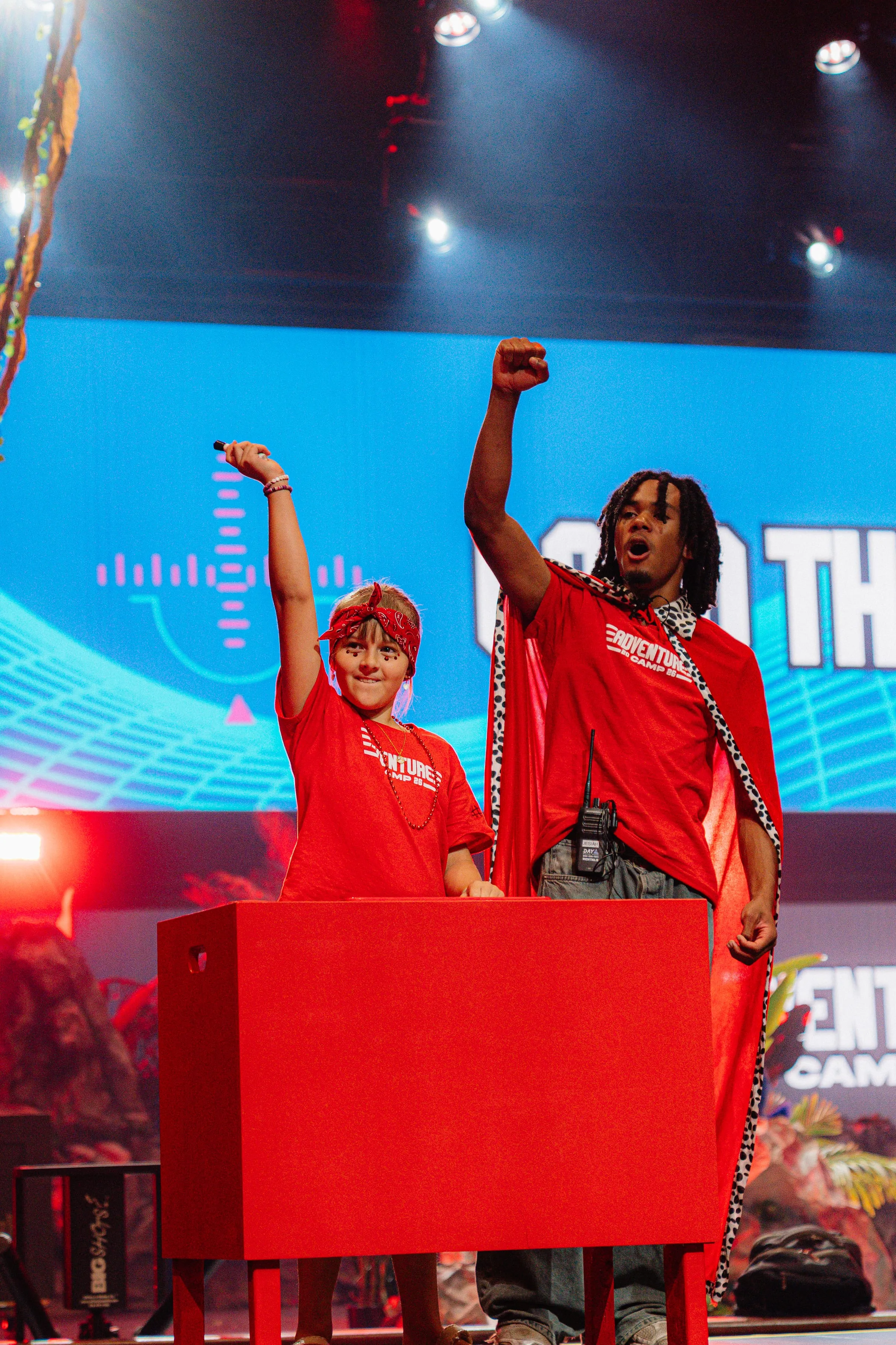 A camper and camp host raise their fists high during an on-stage rally moment.
