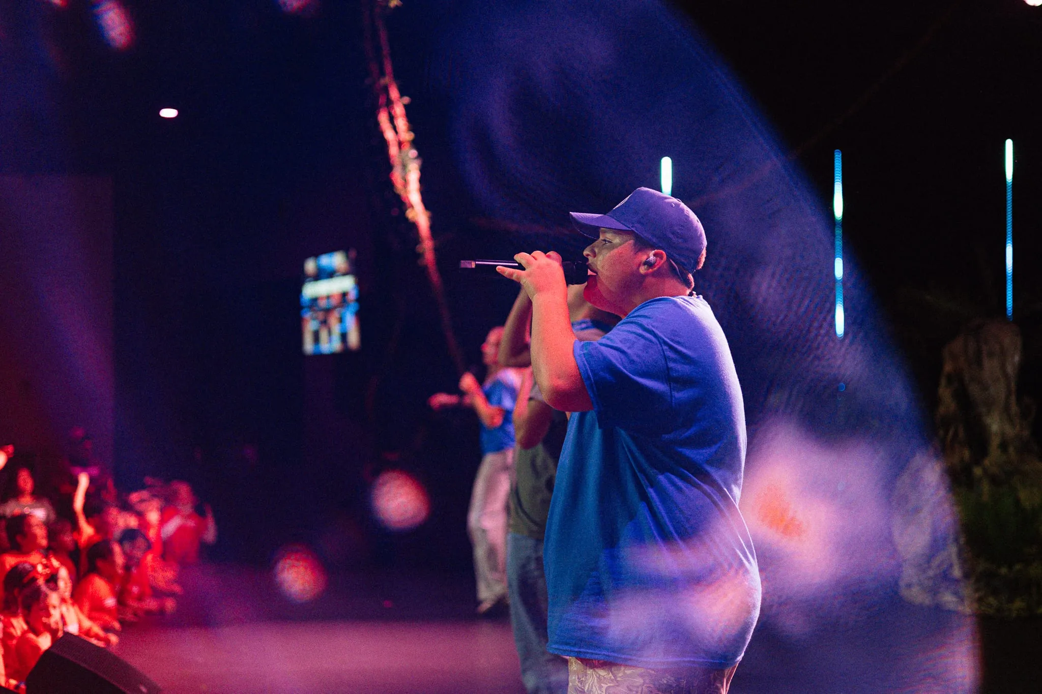 A stage performer sings out to the crowd during an evening program.