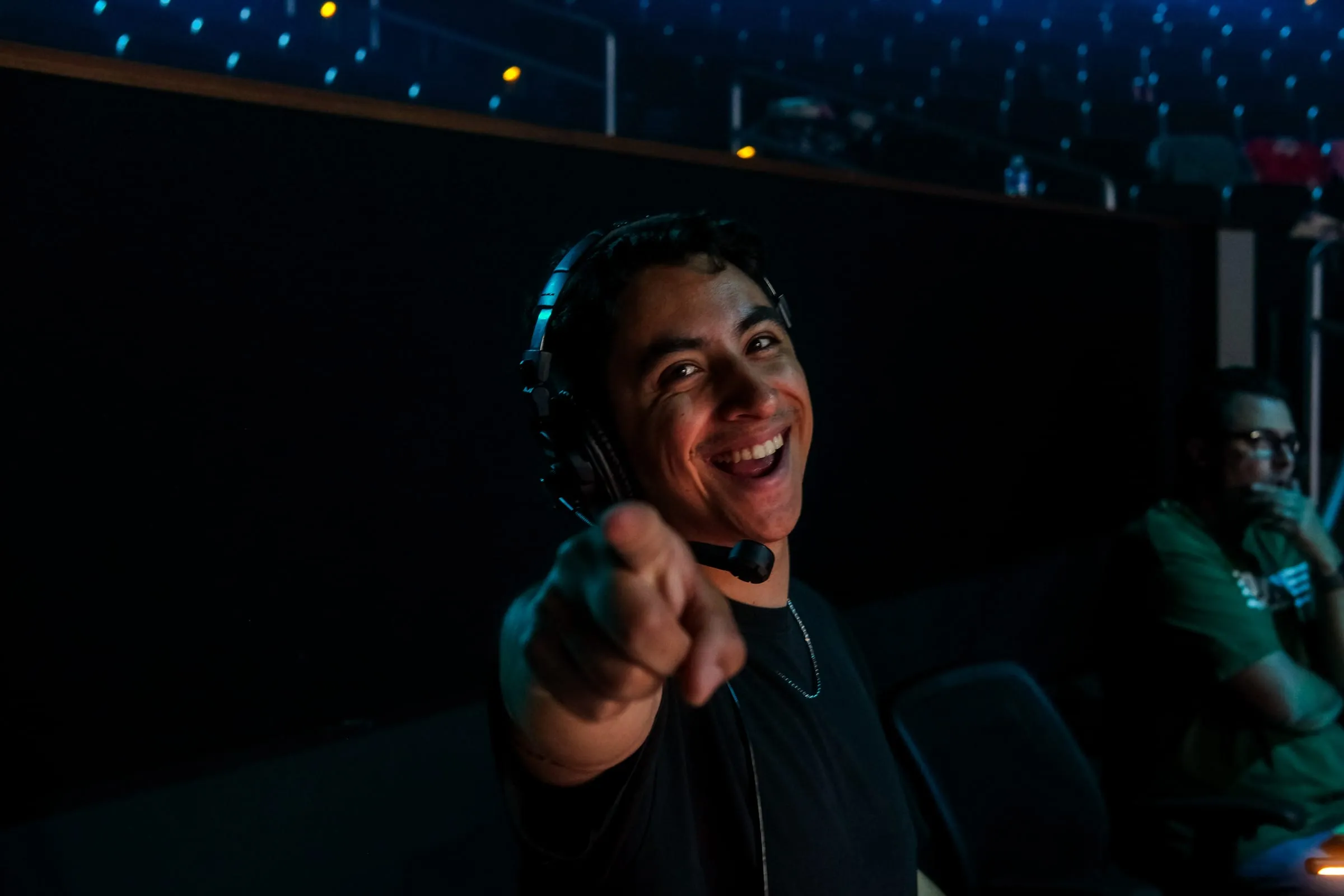 A production volunteer laughs and points at the camera from the light booth.