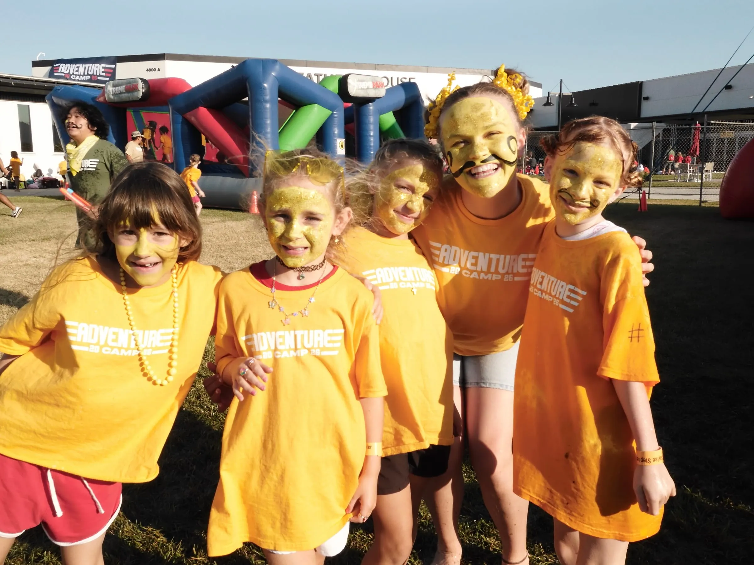 Five campers show off gold glitter face paint after a color-themed afternoon.