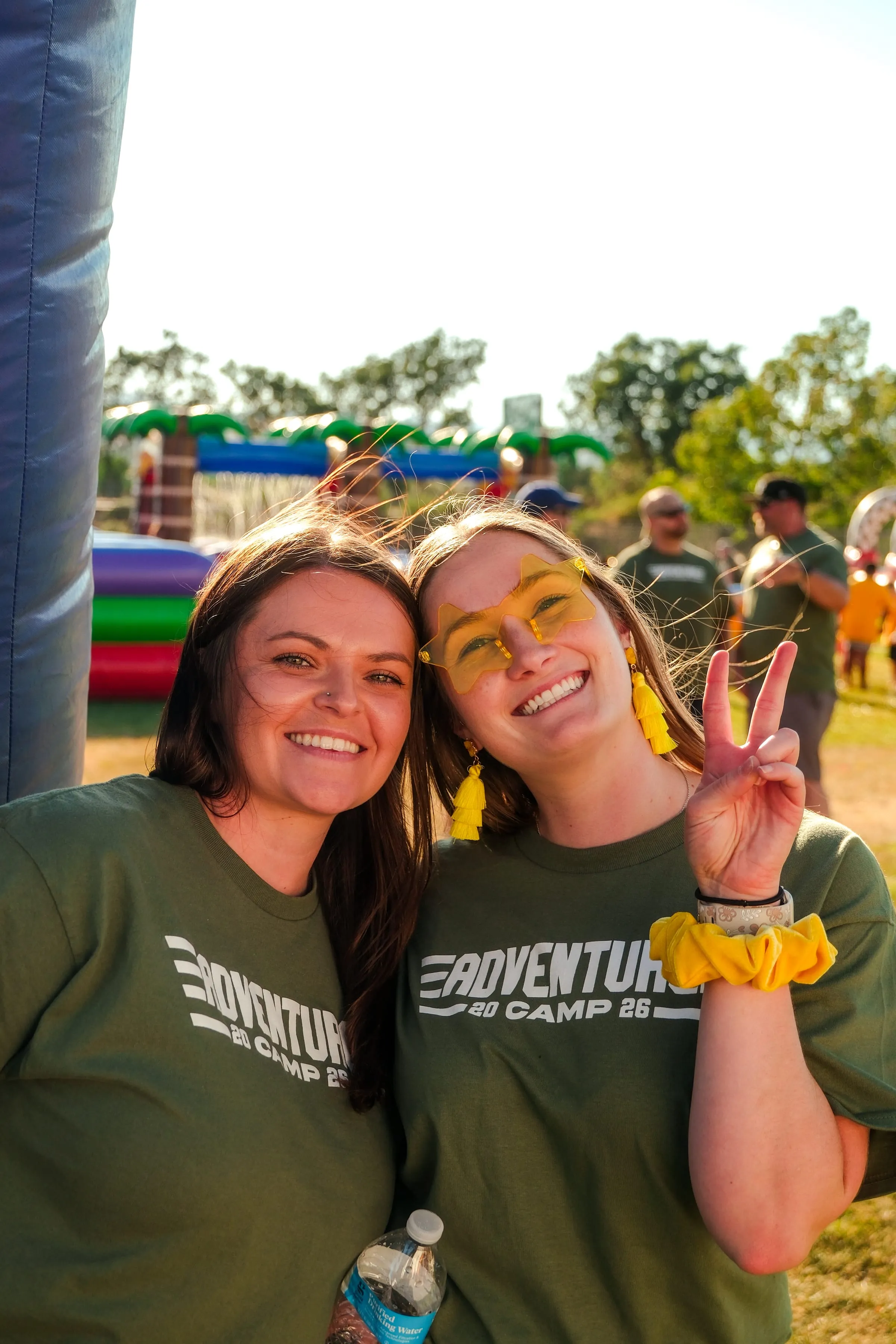 Two camp volunteers pose together in front of the inflatable water slide.